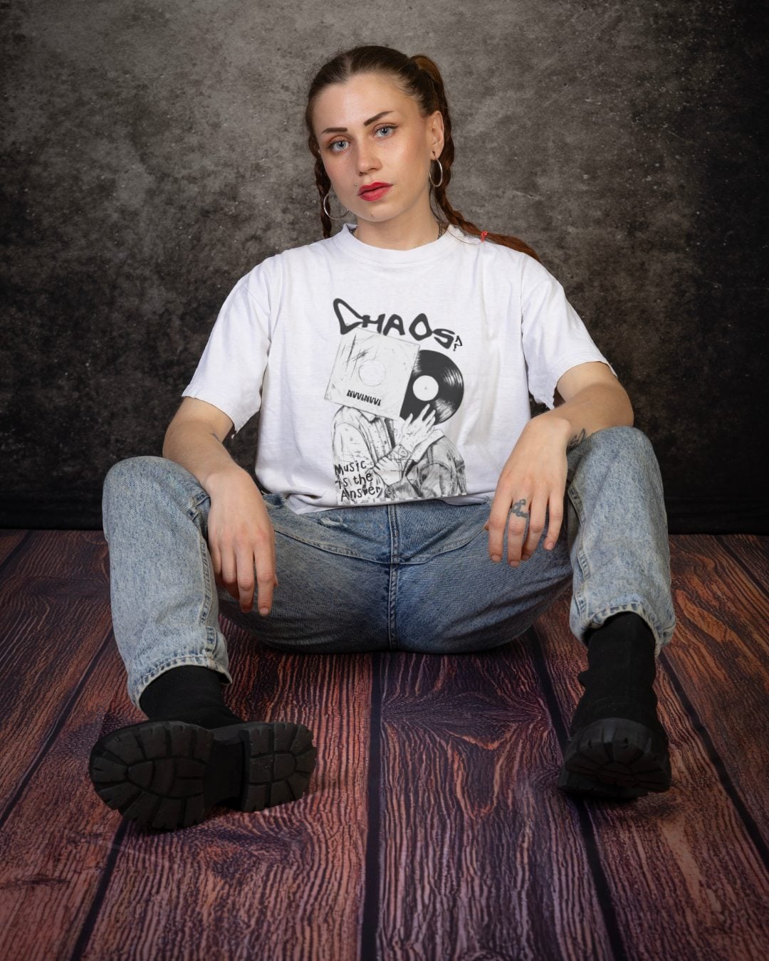 White tee worn from the front, black and white print with the word CHAOS and a figure with a record-player head, seated on the floor.