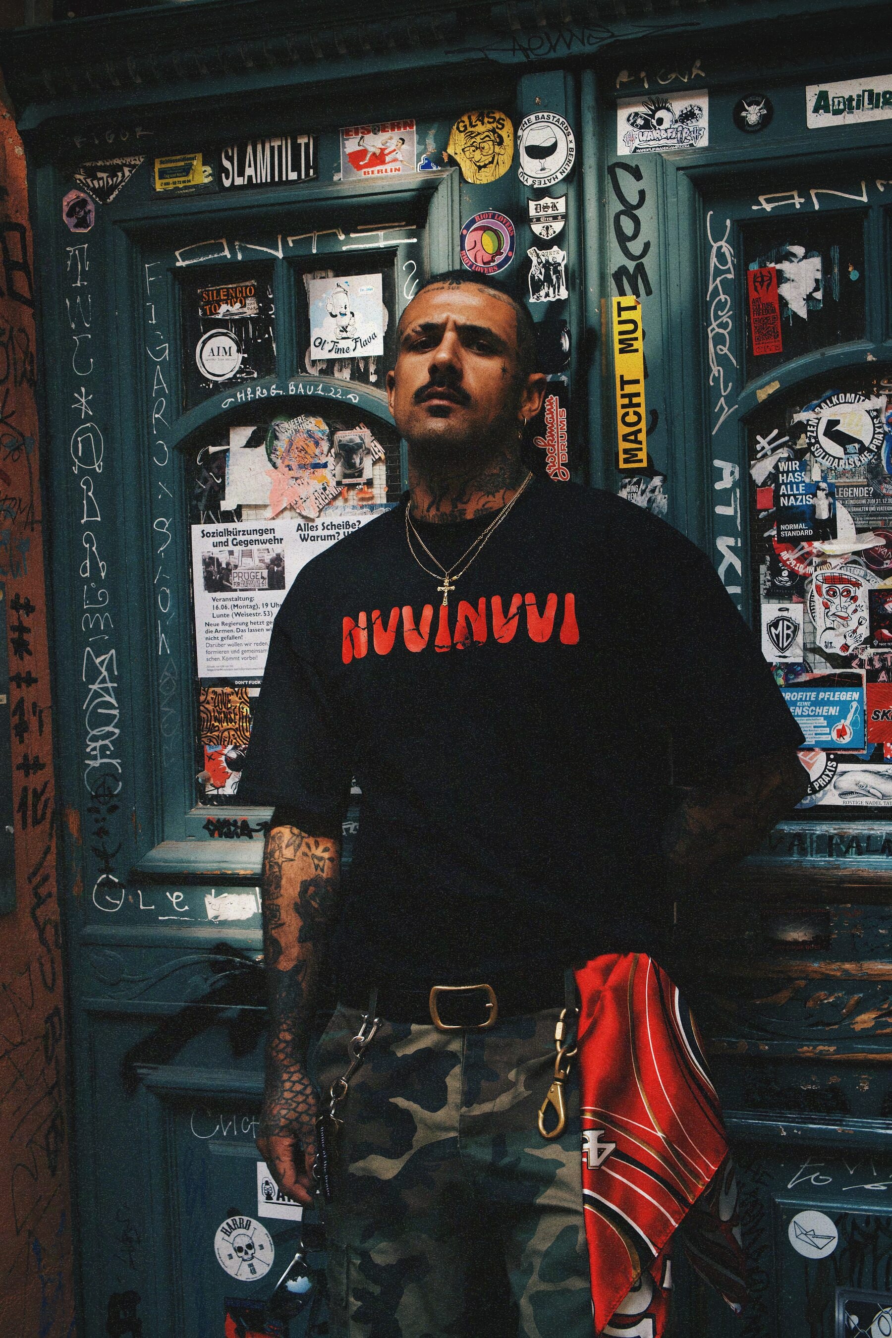 VINV black t-shirt with red NVVINVVI logo, worn full-length in front of a sticker-covered door