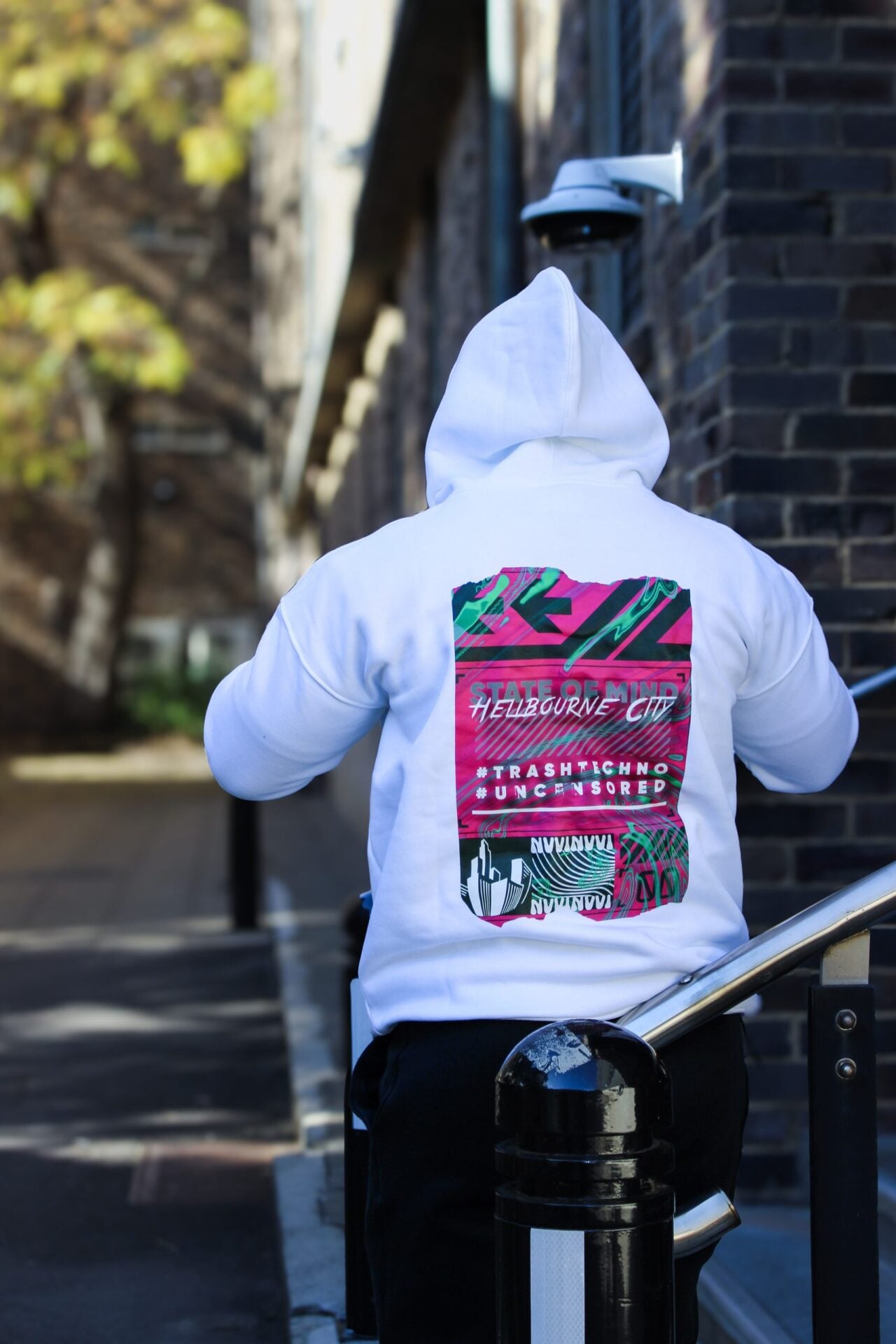 Hoodie blanc porté de dos capuche relevée, impression dorsale Hellbourne City rose.