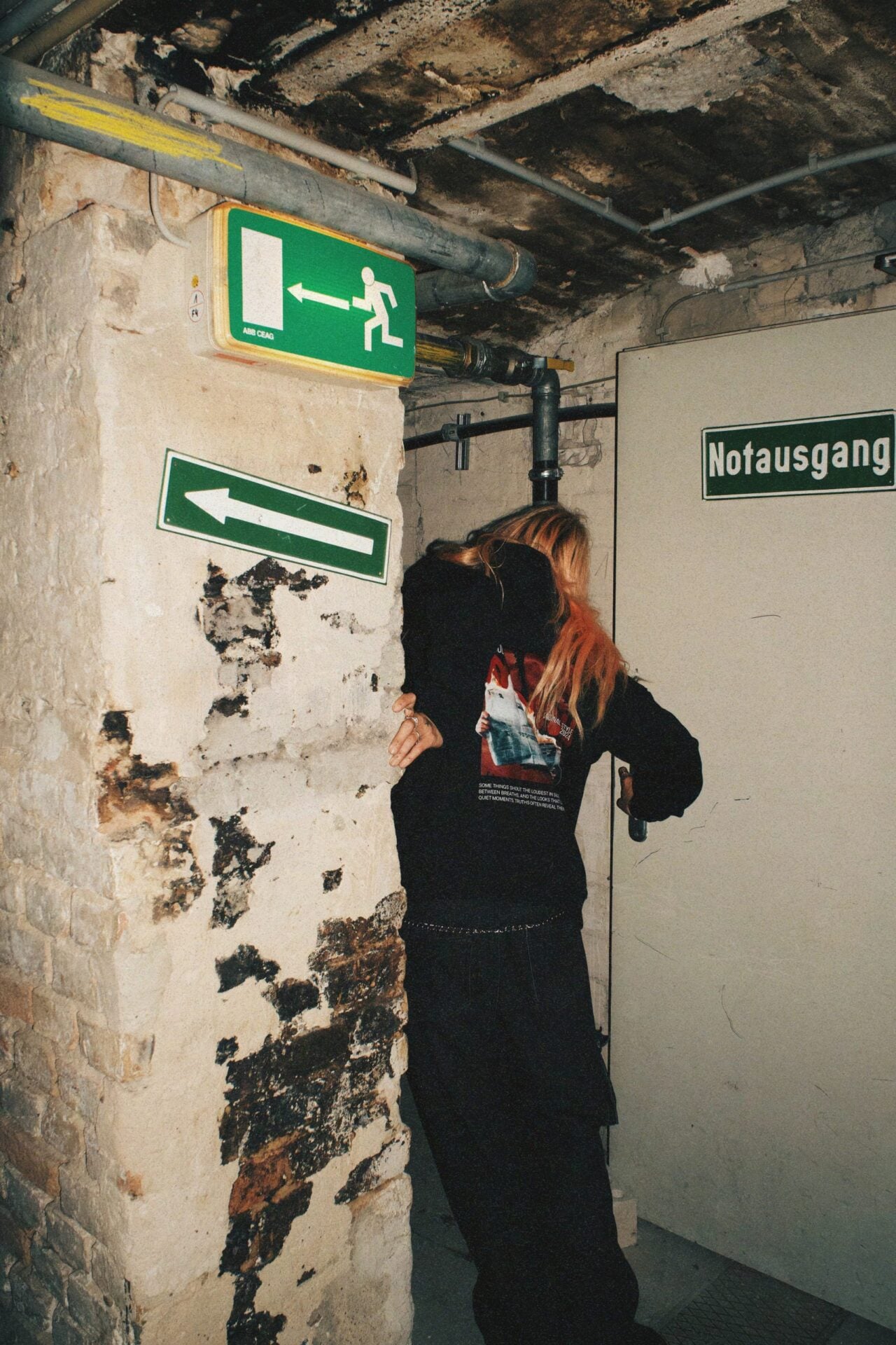 Black zip jacket worn from behind, closer view in the same corridor.