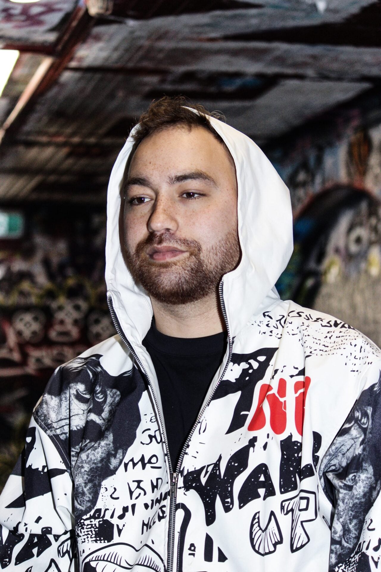 Veste graffiti blanche portée capuche relevée, vue de face rapprochée.