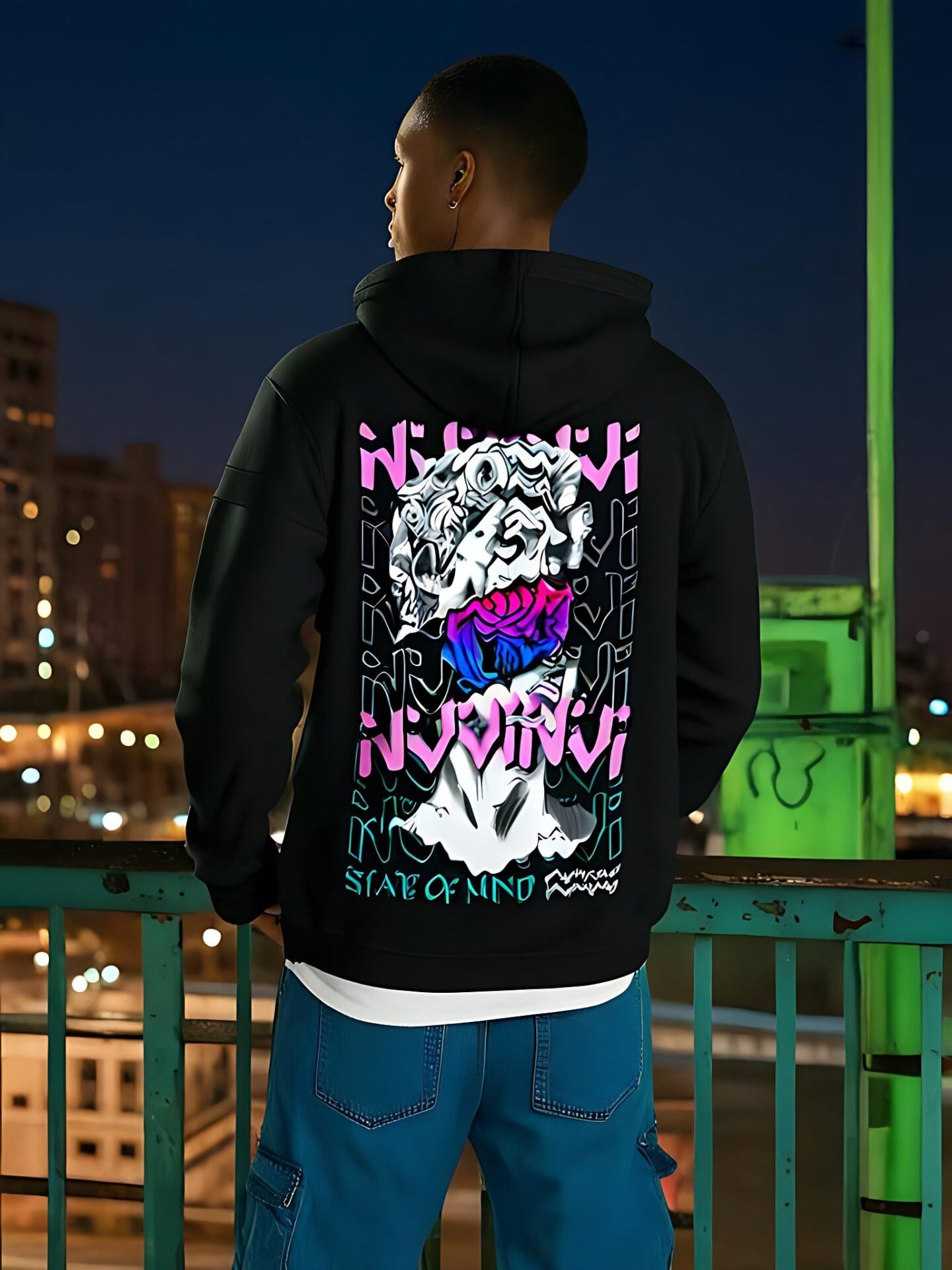 Hoodie noir porté de dos, impression dorsale rose et violette, de nuit sur une passerelle.