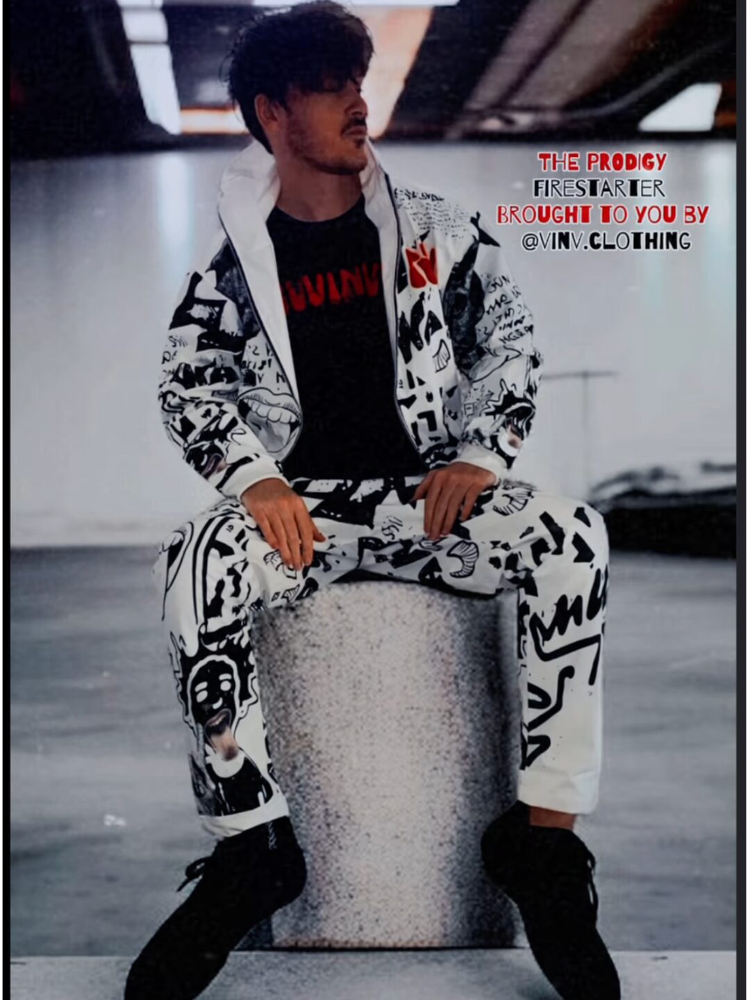 Man wearing the full white and black Firestarter graffiti tracksuit by Vinv Clothing, sitting in a parking garage.